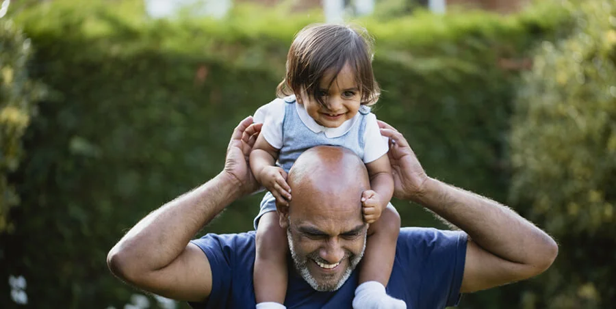 Child on man's shoulders, both smiling